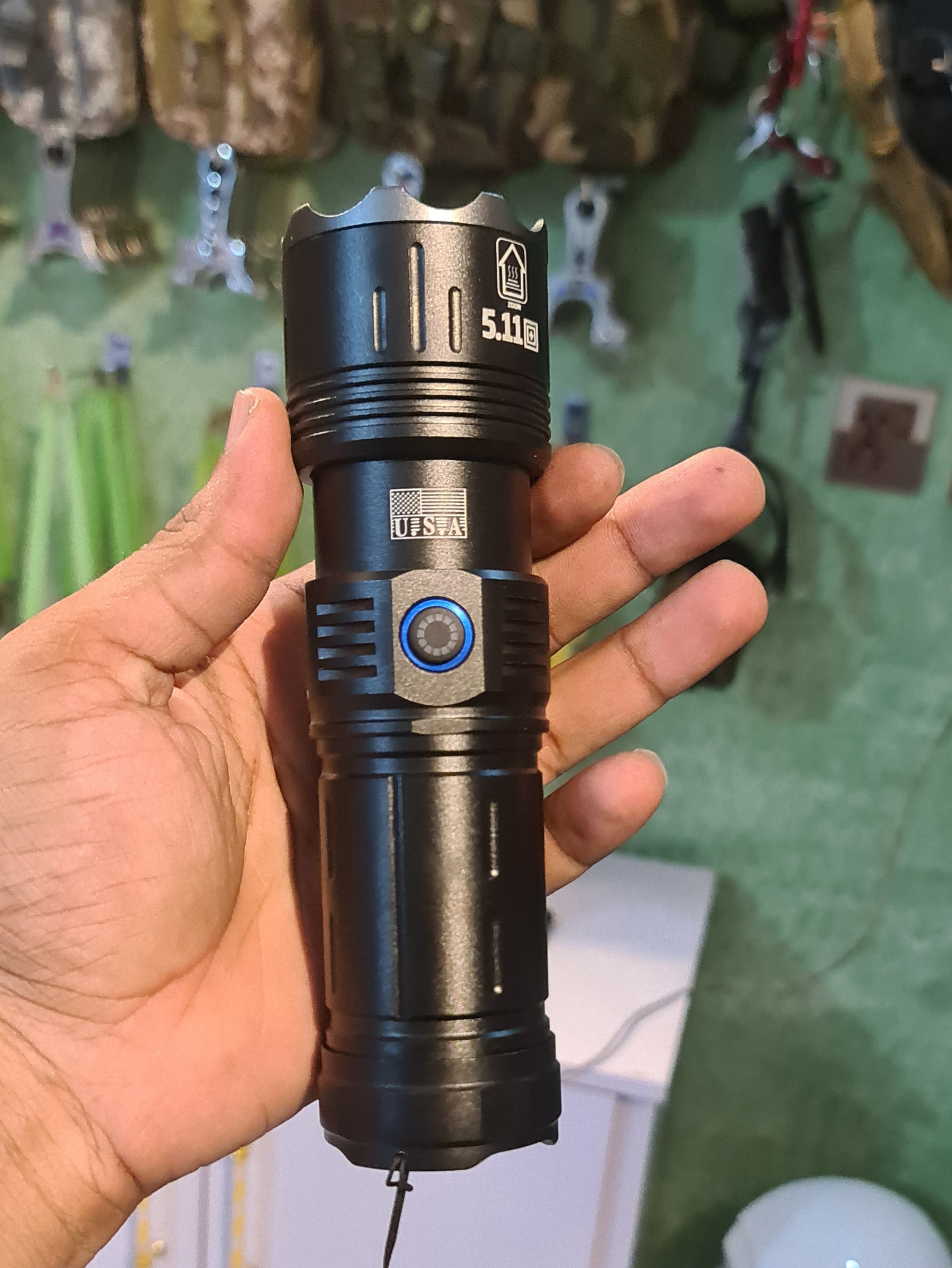 Black handheld rechargeable LED tactical flashlight with an adjustable zoom head and a side power button.